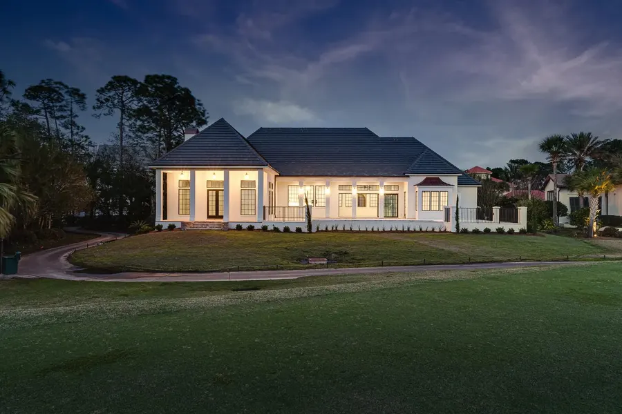 Elegant white estate home glowing at dusk on a golf course