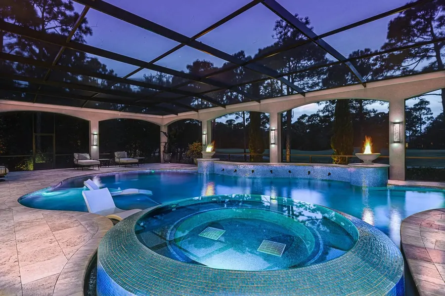 Screened lanai pool and spa with fire bowls at twilight