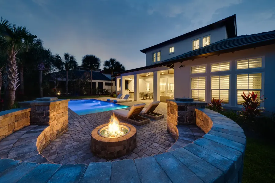 Backyard fire pit and pool at dusk behind a Florida coastal home