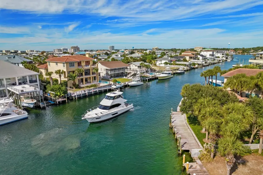 Aerial view of a motor yacht cruising a Destin harbor canal past waterfront homes