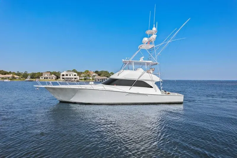 White sportfishing yacht with tall outriggers cruising calm coastal water