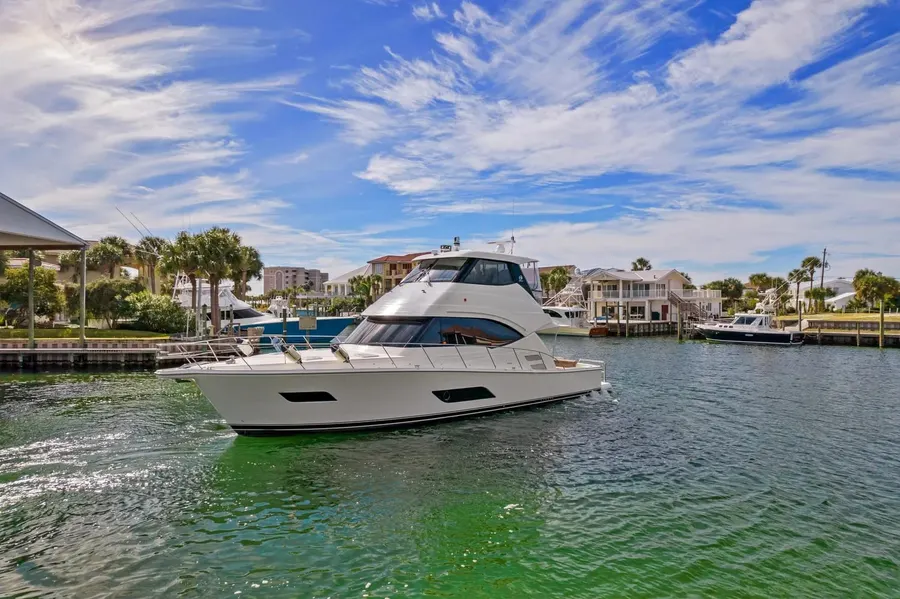 White motor yacht idling through a palm-lined Destin canal