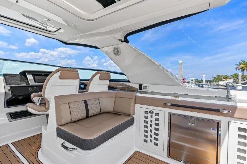Boat cockpit lounge with tan seating, wet bar, and stainless fridge
