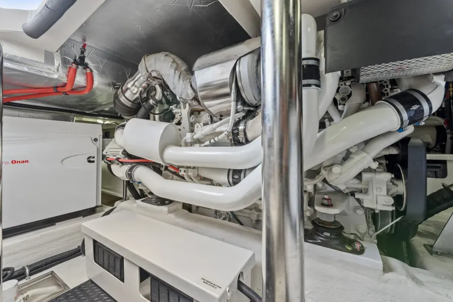 Yacht engine room showing twin engines, generator, and white plumbing