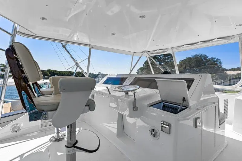 Sportfish flybridge helm with white console and captain seats under canvas