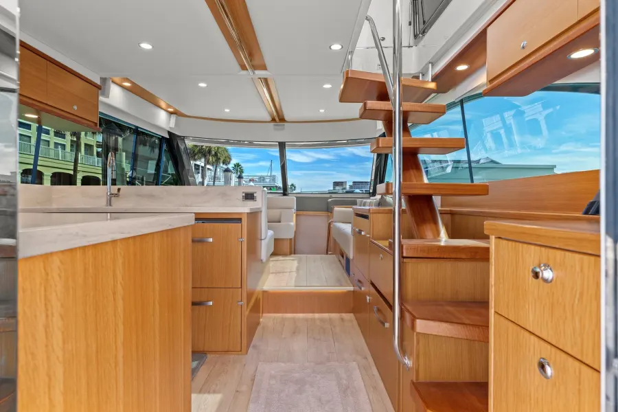 Yacht galley and salon with warm teak cabinetry and marble countertop