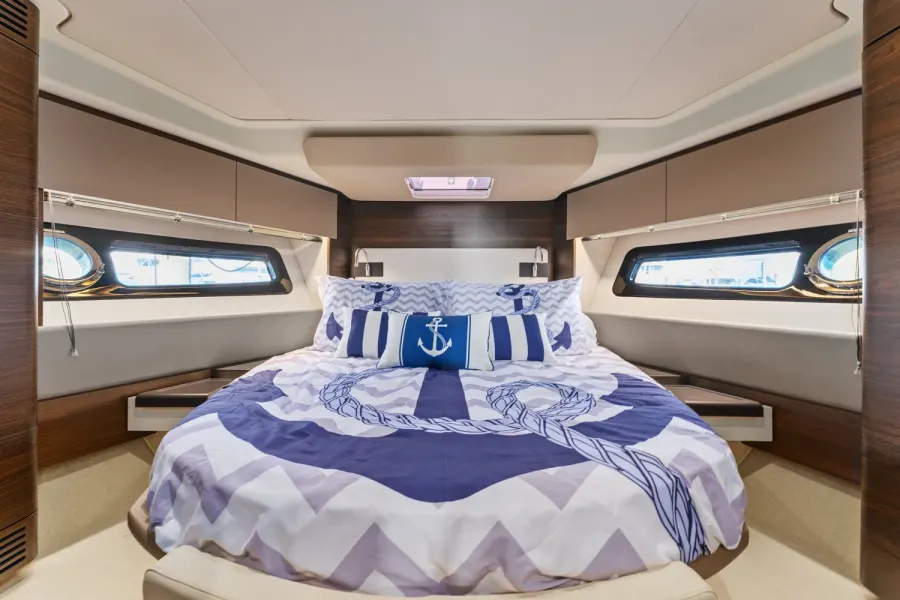 Forward stateroom with nautical anchor bedding and portlight windows