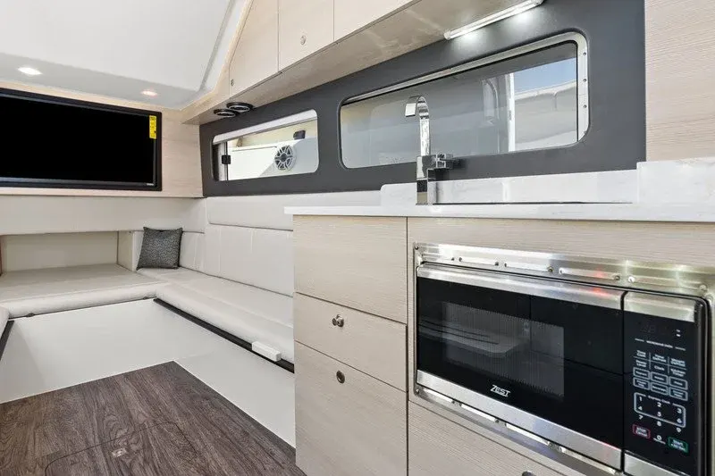 Yacht cabin galley with microwave, TV, and wraparound white seating