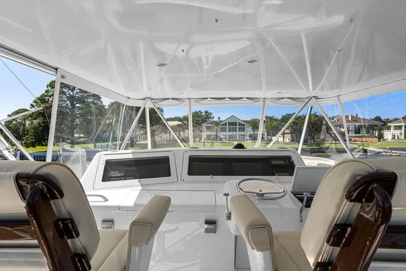 Flybridge helm with twin captain chairs overlooking a waterfront home
