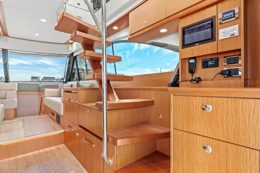 Teak yacht interior with staircase, electronics panel, and lounge seating
