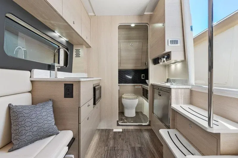 Light wood yacht cabin galley leading to a private head