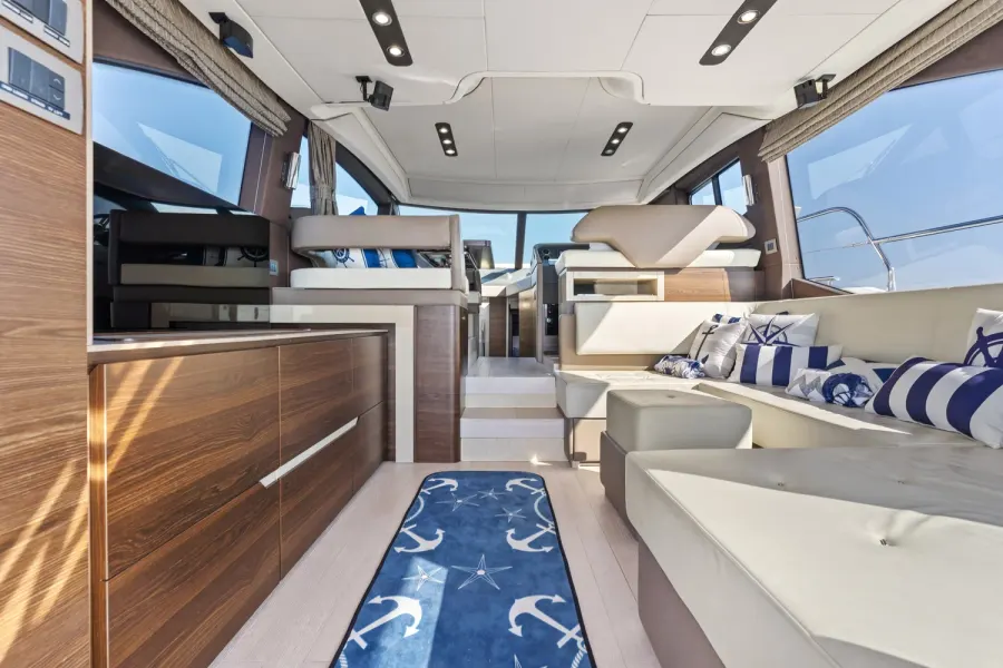 Yacht salon with walnut cabinetry, nautical anchor rug, and cream seating