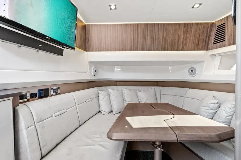 Curved cabin dinette with plush cushions and mounted flatscreen TV