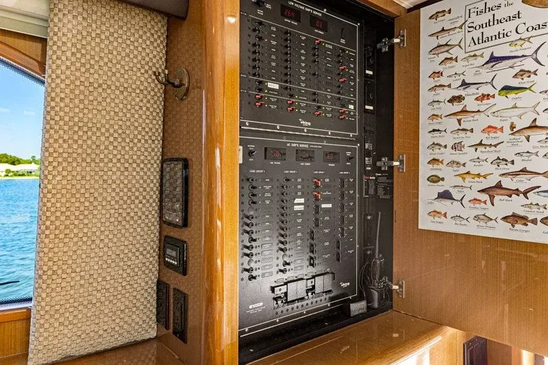Onboard electrical panel with breaker switches beside a fish species poster