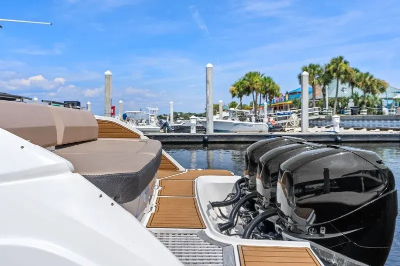 Triple outboard engines on a boat docked at a palm-lined Florida marina