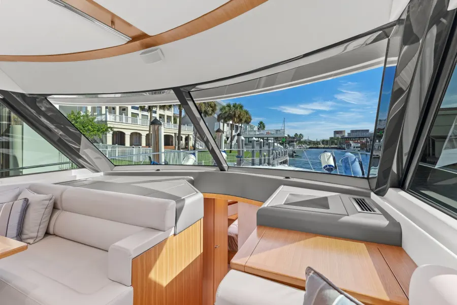 Bright yacht salon seating with panoramic windows overlooking Destin harbor homes