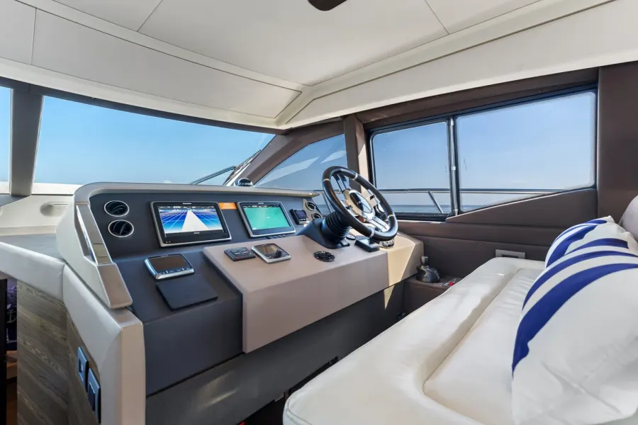Yacht helm station with dual navigation screens and leather-wrapped wheel